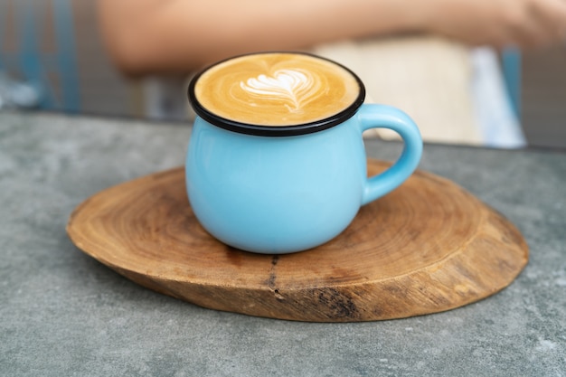 Taza de café en vidrio azul en placa de madera