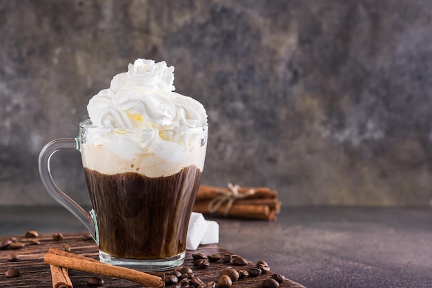 Taza de café vienés con crema batida y canela sobre la mesa