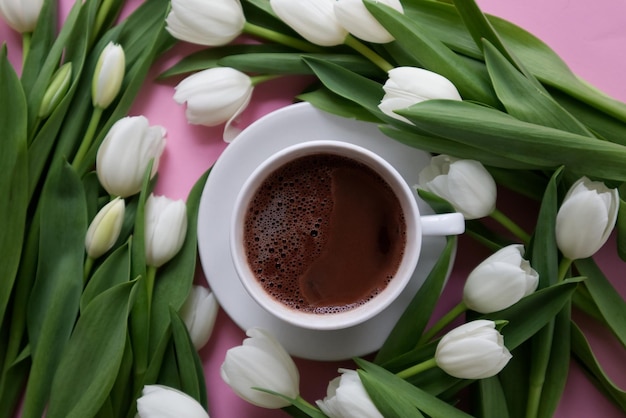 Taza de café entre vista superior de tulipanes blancos dispuestos