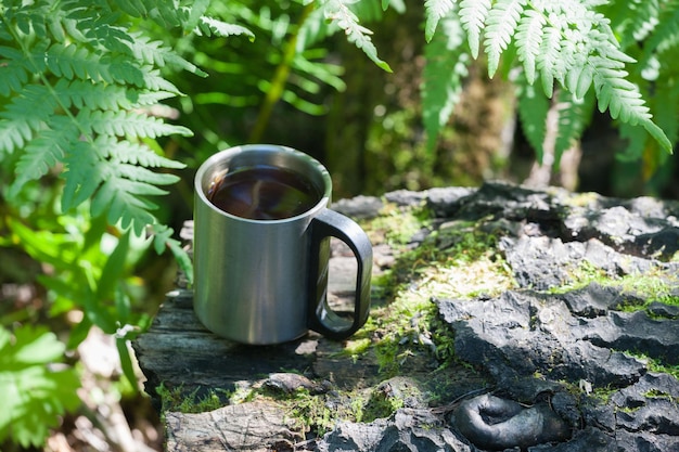 Una taza de campamento con un café en un bosque salvaje en un obstáculo