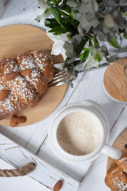 Una taza de capuchino aromático y un croissant en una bandeja blanca Marzo Abril Mayo