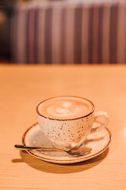 Una taza de capuchino aromático está sobre una mesa en un café