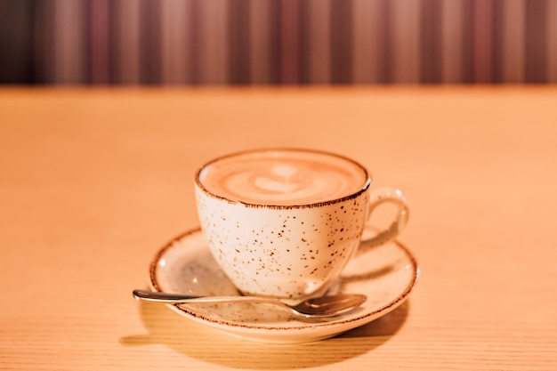 Una taza de capuchino aromático está sobre una mesa en un café