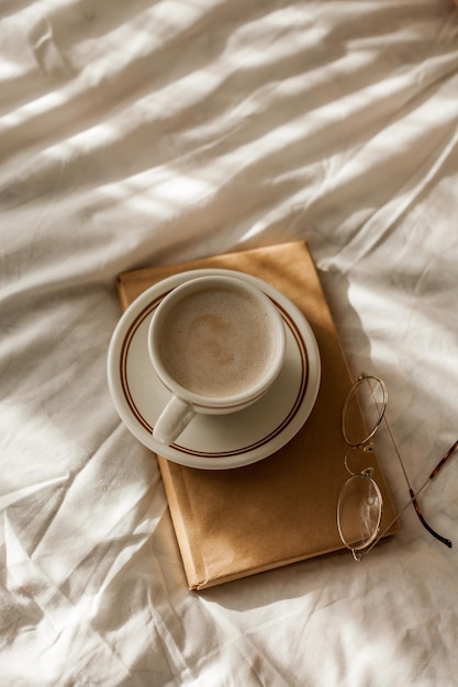 Una taza de capuchino caliente unas copas de libro en la cama Desayuno Casa acogedora Detalles de decoración