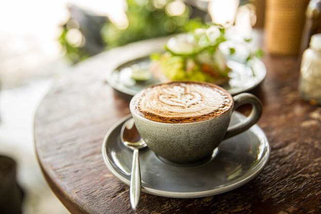 Taza de capuchino caliente sobre la mesa de madera