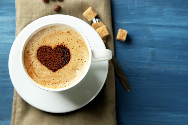 Taza de capuchino con corazón de cacao en mesa de madera