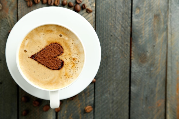 Taza de capuchino con corazón de cacao en mesa de madera