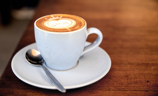 Taza de capuchino está sobre la mesa de textura de madera