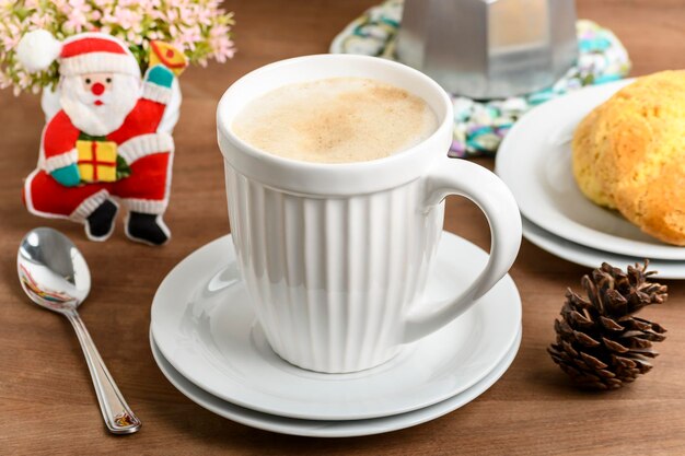 Una taza con capuchino, unas galletas a un lado y adornos navideños, recordando la proximidad de la fecha navideña