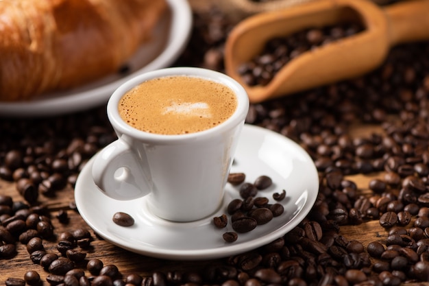 Una taza de capuchino con granos de café como fondo de cerca