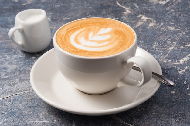 Taza de capuchino mediana sobre un fondo gris