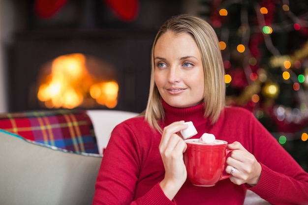 Taza de la celebración rubia y comer malvavisco en Navidad