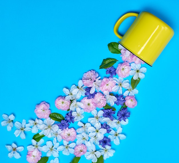 Taza de cerámica amarilla y capullos de flores.