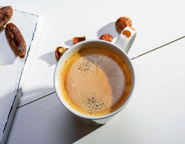 Taza de cerámica blanca con café negro y espuma.