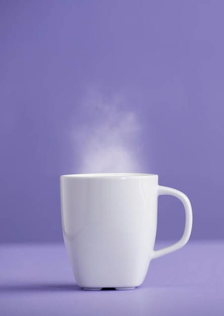 Taza de cerámica blanca de café o té con vapor caliente con un fondo morado muy peri