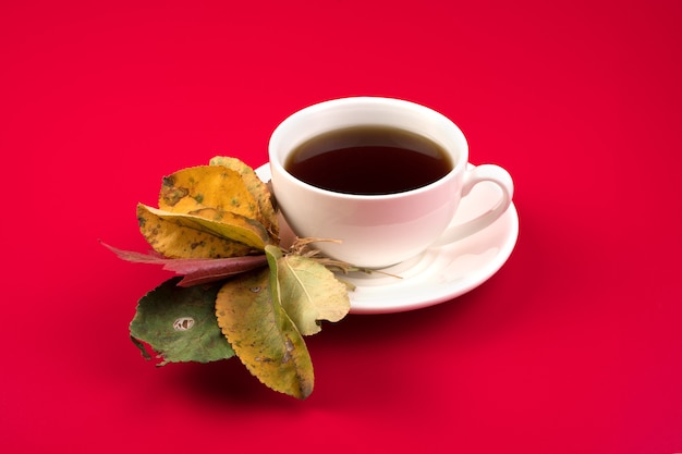 Taza de cerámica con café caliente y hojas de otoño.