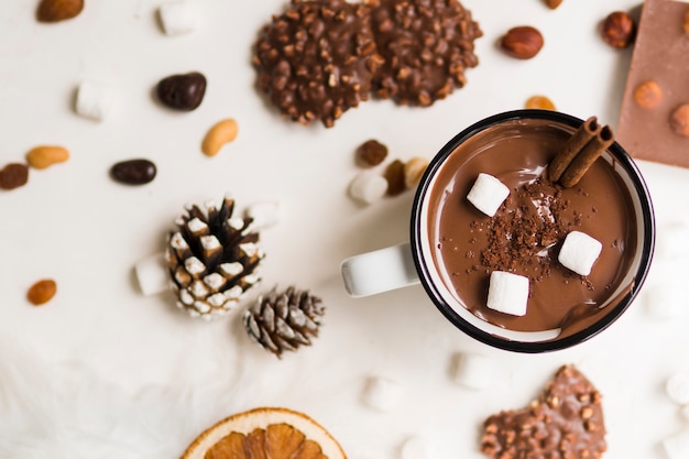 Foto taza de chocolate caliente con canela y malvaviscos.