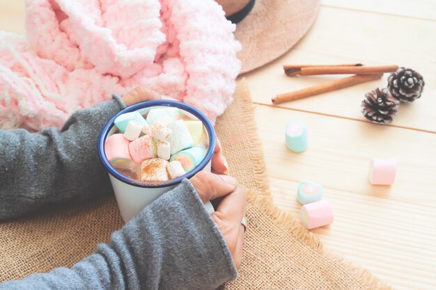 Una taza de chocolate caliente con malvaviscos pastel en manos de la mujer. Estilo de vida acogedor.