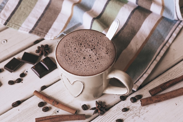 Taza de chocolate caliente con malvaviscos y ramitas de canela