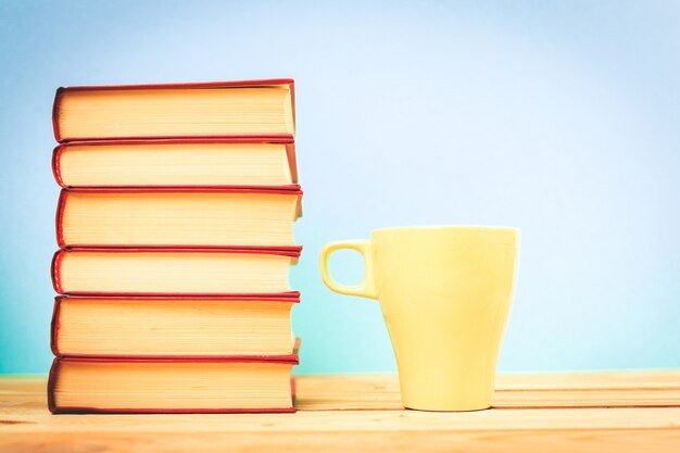 Taza de color de té con libros en la mesa