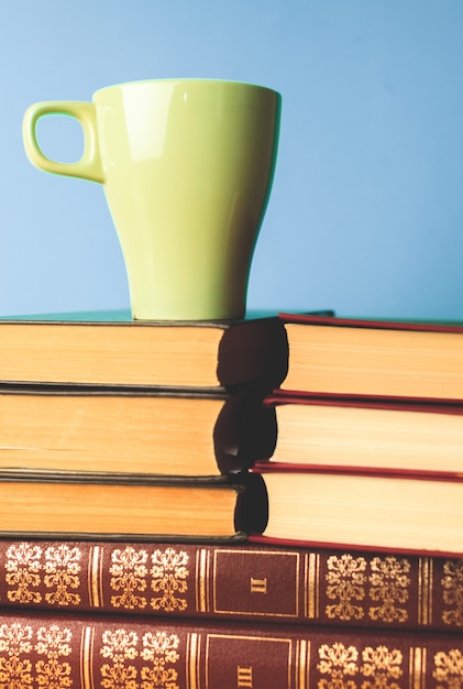 Taza de color de té con libros en la mesa