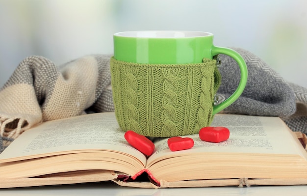 Taza con cosa tejida y libro abierto de cerca