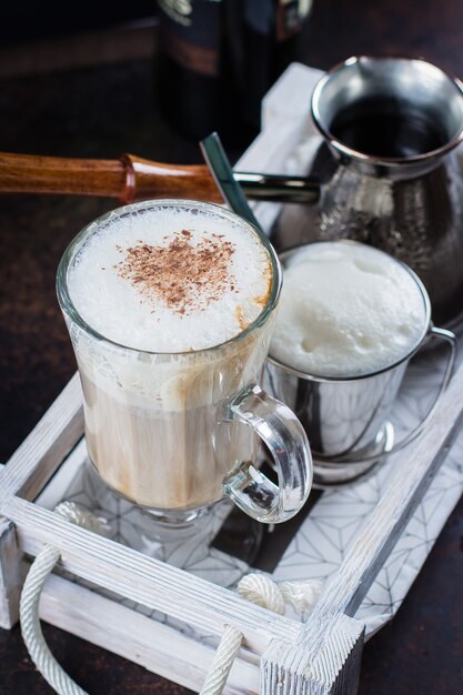 Taza de cristal de café con leche en bandeja de madera