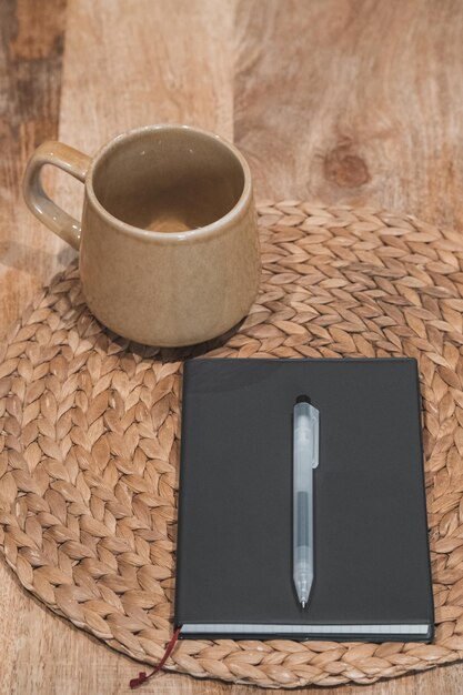 Taza de cuaderno y bolígrafo en la mesa