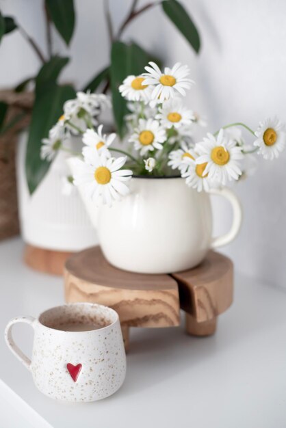 Una taza de delicioso café aromático en una taza blanca sobre un fondo verde Margaritas cercanas