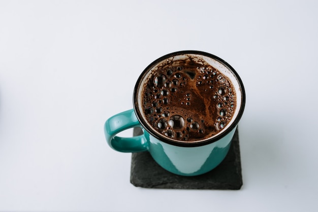 Taza del esmalte de la turquesa con café sólo en el práctico de costa negro.
