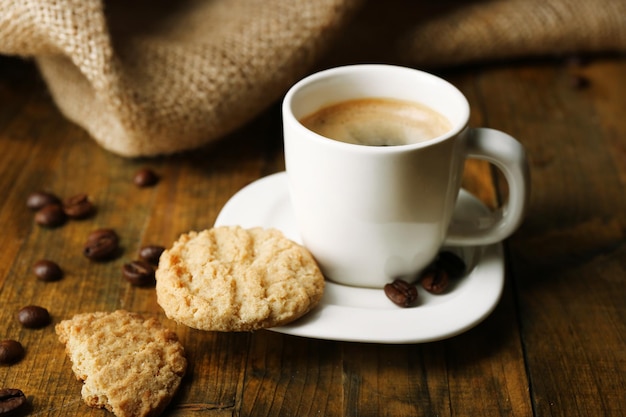 Taza de espresso y sabrosa galleta sobre fondo de madera