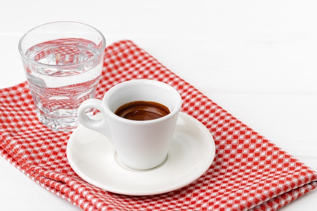 Taza de espresso con un vaso de agua en el cuadro blanco