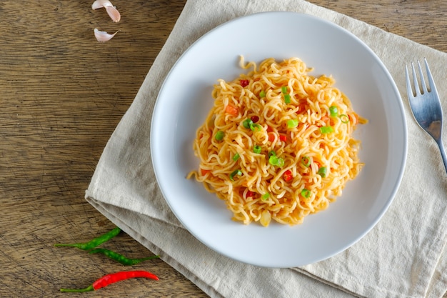 Una taza de fideos instantáneos colocados en una mantelería Con chile como ingredientes fideos y espacio de copia