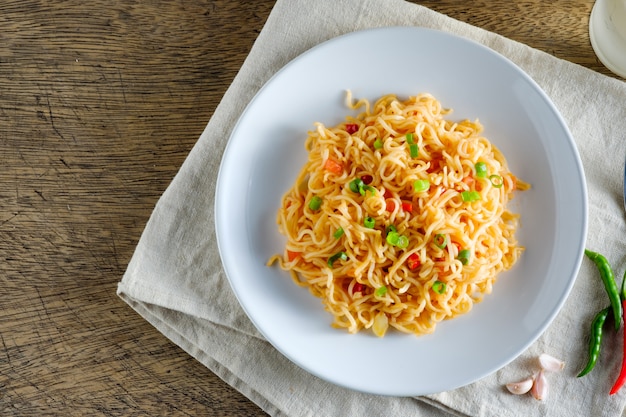 Una taza de fideos instantáneos colocados en una mantelería Con chile como ingredientes fideos y espacio de copia