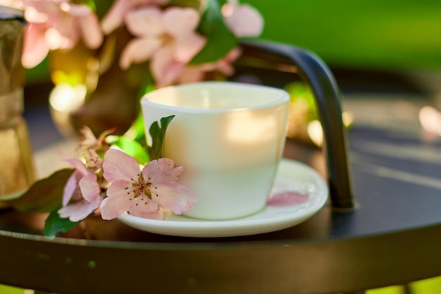 Taza de flores de café y cuaderno en la pequeña mesa negra