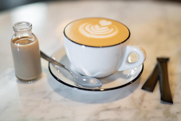 Una taza fragante y cálida de capuchino con un corazón de dibujo en la mesa