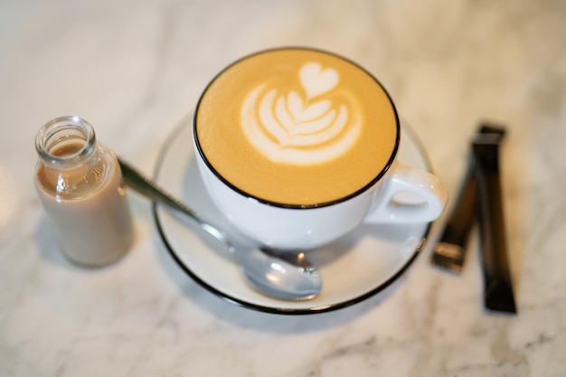 Una taza fragante y cálida de capuchino con un corazón de dibujo en la mesa