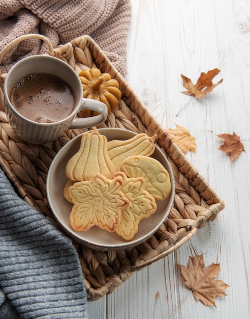 Taza de galletas de café en bandeja de hojas amarillas