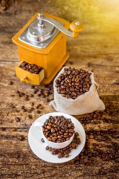 Taza de granos de café Molinillo de café y bolsa con granos de café en el fondo