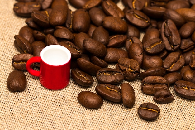 Taza y granos de café en el saco de tela