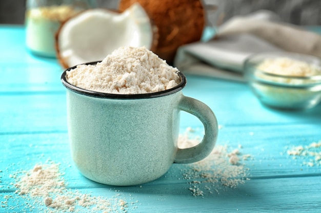 Taza con harina de coco sobre fondo de madera