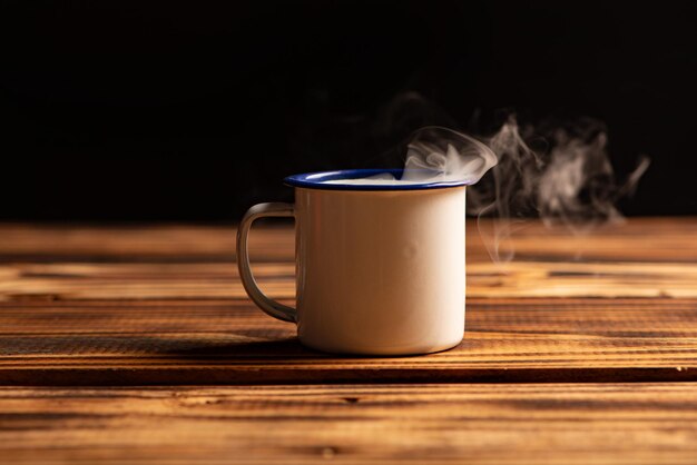 Taza con humo taza de café blanca en madera rústica que libera humo fondo oscuro enfoque selectivo