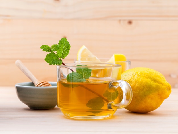 Taza de infusión de hierbas con menta verde fresca, miel y limón sobre fondo de madera.