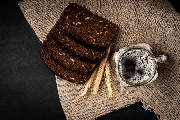 Taza de kvas con pan de centeno sobre fondo negro.