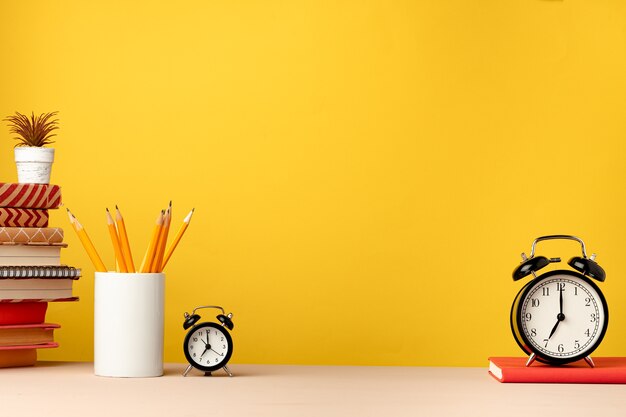 Taza de lápices y blocs de notas en el escritorio contra amarillo