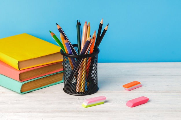 Taza de lápices de colores y pila de libros sobre la mesa