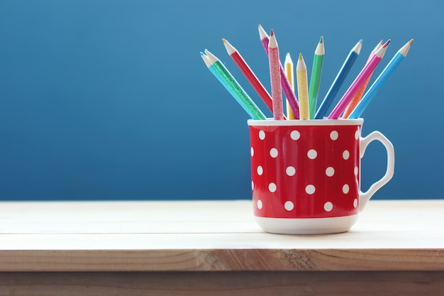 Foto taza con lápices de colores sobre una mesa de madera