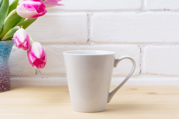 Taza de latte blanca con tulipán magenta