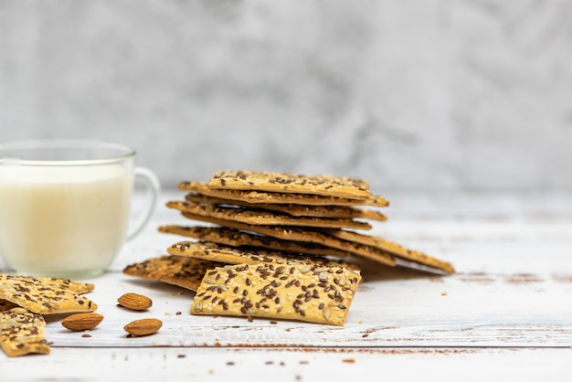 Taza de leche de almendras y pila de galletas integrales en luz.