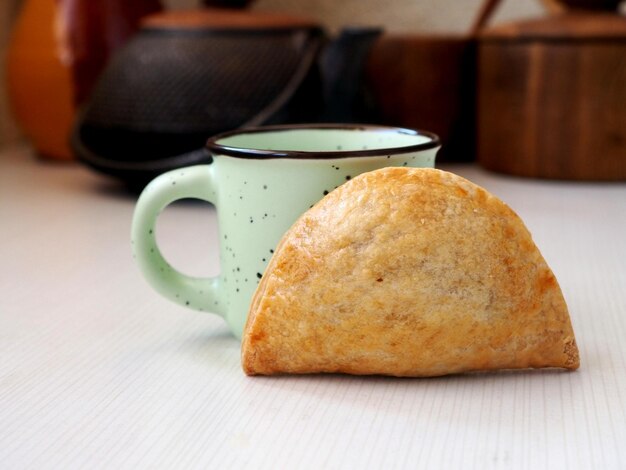 Una taza con leche y una empanada